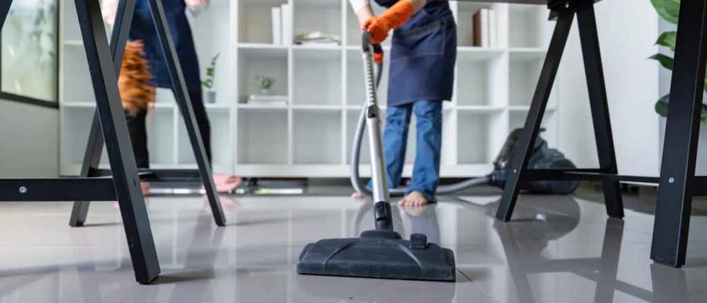 עובד ניקיון שואב מתחת לשולחן משרדי